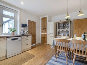 Eine moderne Küche mit Holzschränken, einem eingebauten Geschirrspüler und einem Essbereich mit Holztisch und -stühlen.