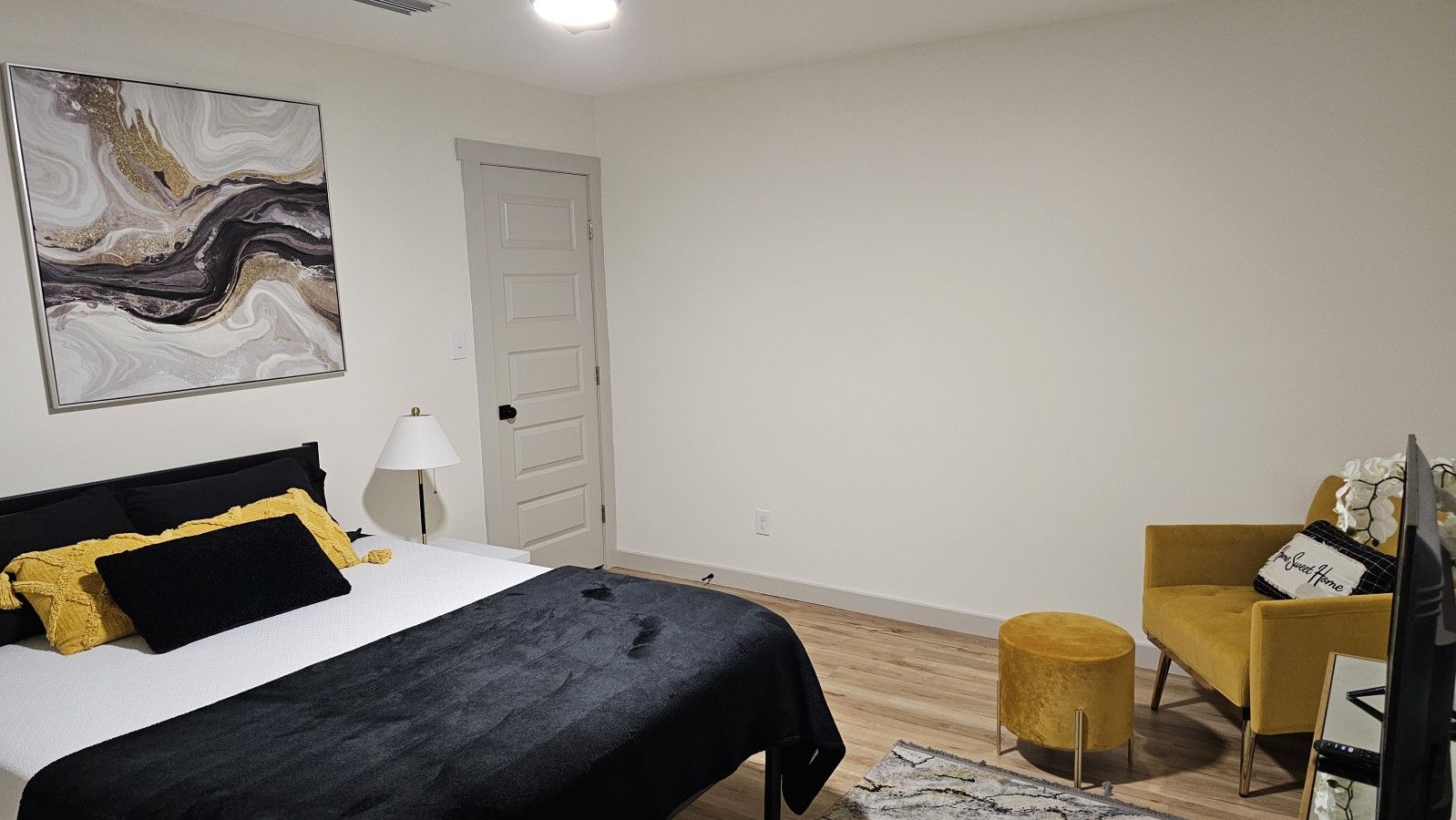 Une chambre à coucher avec un lit, une chaise, un téléviseur et une porte.