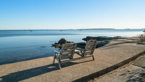 A concrete bench by a calm sea with clear skies. - Oceanside Cottage with Private Beach Access (Mattapoisett)