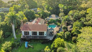 A house with a swimming pool, surrounded by lush greenery and palm trees. - Ocean Shores Oasis  (Ocean Shores)