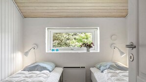 A small, well-lit bedroom with two beds, a window with a view of trees, and a radiator. - Beautiful home in Vestervig with sauna (Vestervig)