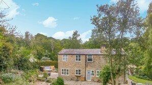 A stone house with a small pond, surrounded by lush greenery and trees. - Humford Mill Cottage (Humford Mill near Bedlington)