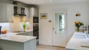 A modern kitchen with white cabinetry, a central island, and built-in appliances. - Humford Mill Cottage (Humford Mill near Bedlington)