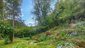 A lush garden with a variety of plants and flowers, a small pond, and a stone pathway. - Humford Mill Cottage (Humford Mill near Bedlington)