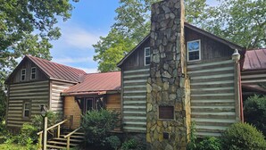 A rustic log cabin with a stone chimney, wooden exterior, and a small porch. - Rustic Cabin on Homestead Farm (Dobson)