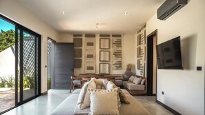 Een moderne woonkamer met een grote bank, een eettafel en een flatscreen televisie aan de muur.