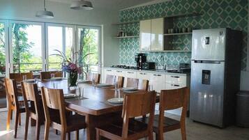 A modern kitchen with a dining table set for six, a refrigerator, and a coffee maker.