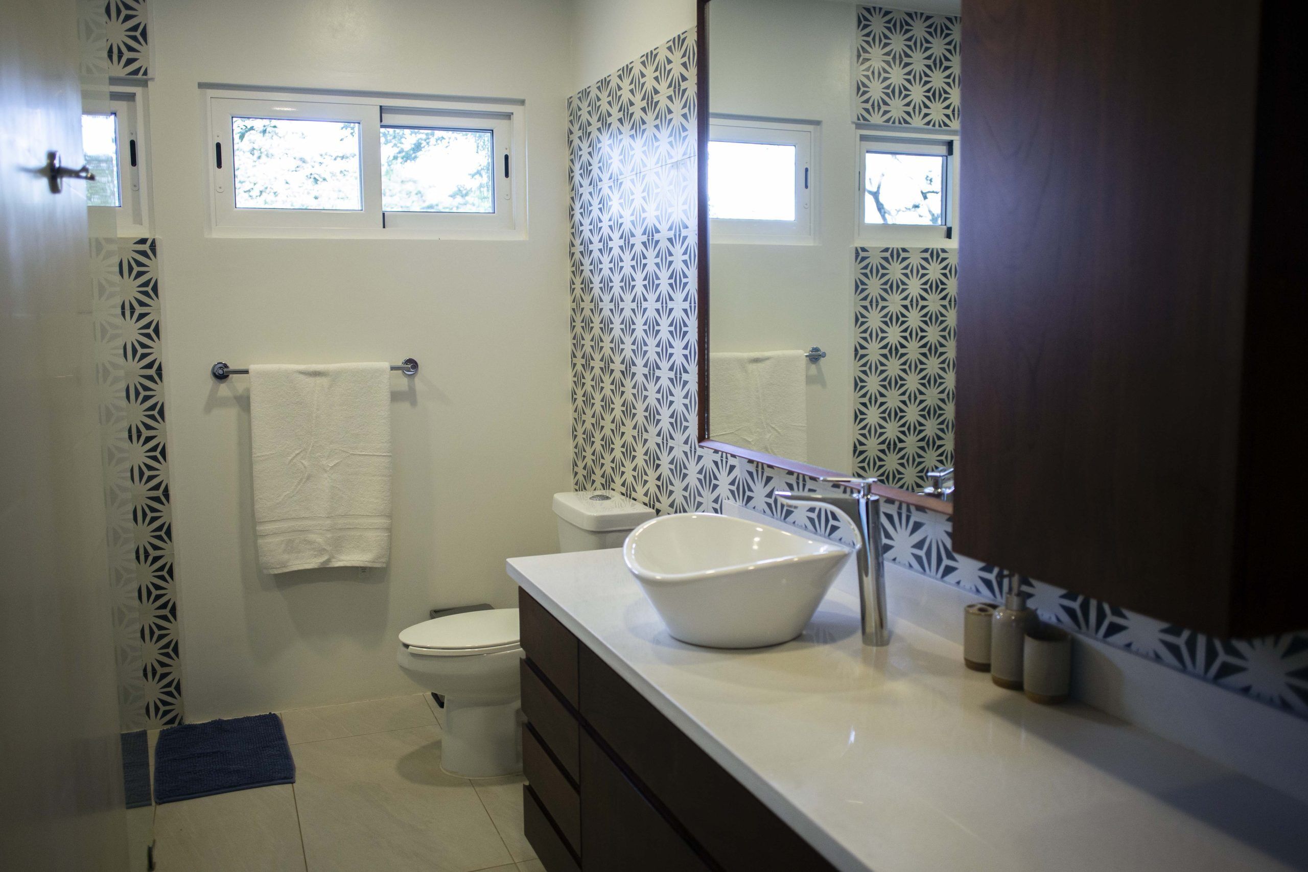 A bathroom with a white sink, a large mirror, and a toilet.