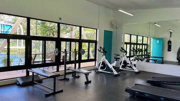 A gym with exercise equipment, large windows, and a view of an outdoor area.