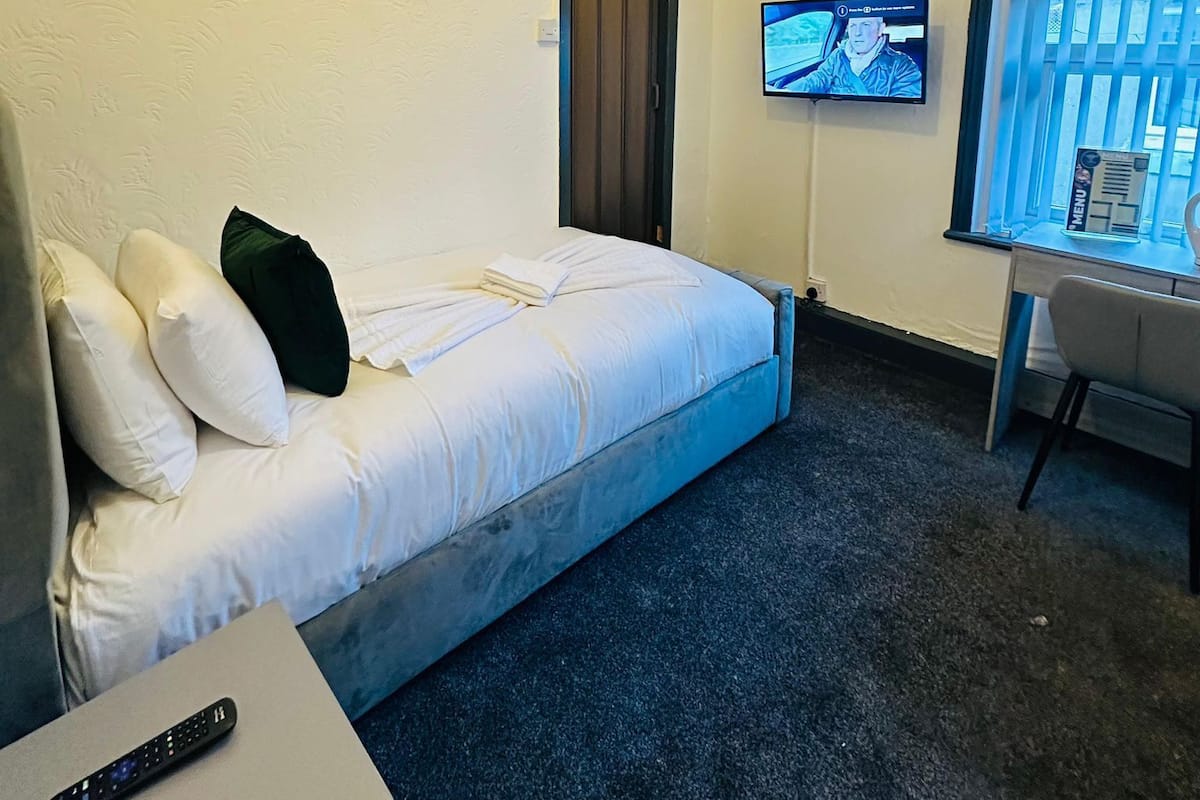 A hotel room with a bed, a desk, a television, and a window.