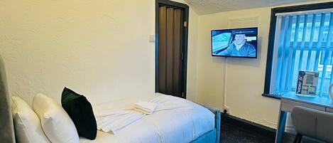 Una camera d'albergo con un letto, una scrivania, un televisore e una finestra.