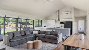 Una sala moderna con un sofá seccional gris, una mesa de centro de madera y una mesa de comedor con sillas.