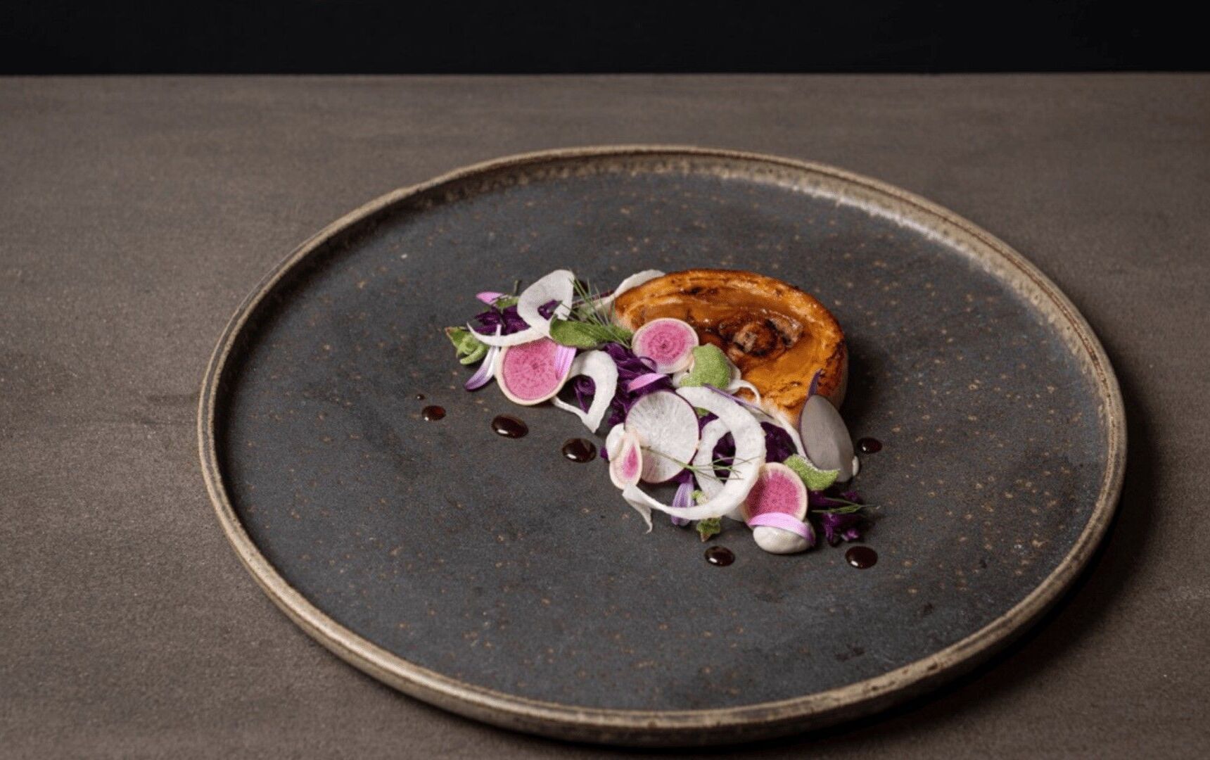 A round plate with a piece of food and some garnishes.