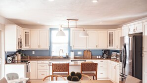 A modern kitchen with white cabinets, a wooden dining table, and a built-in oven.