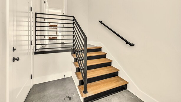 A staircase with wooden steps and a metal railing, leading to an upper floor. - AllSaints +9 beds+ 4bd/4.5ba stunning rooftop views near Broadway (Nashville)
