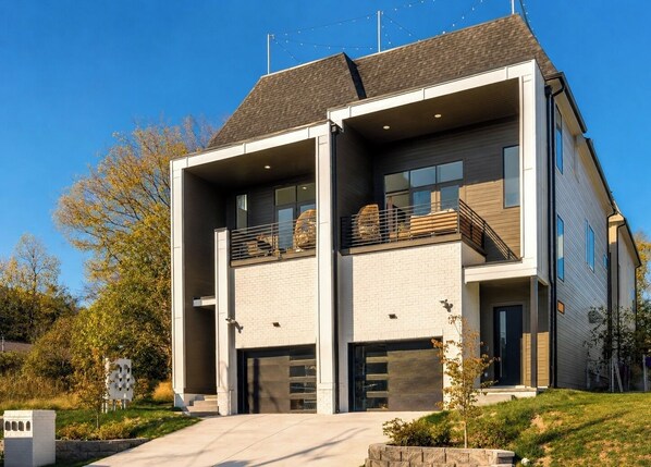 A modern two-story house with a garage, a balcony, and a well-maintained lawn.