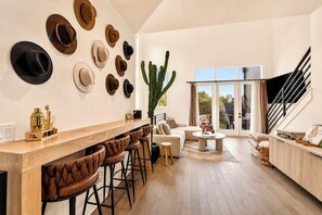 A modern living space with a bar area, multiple seating options, and a large cactus plant. - AllSaints +9 beds+ 4bd/4.5ba stunning rooftop views near Broadway (Nashville)