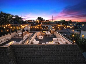 A rooftop patio with outdoor seating, string lights, and a fire feature.
