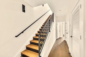 A staircase with wooden steps and black railings, leading to a landing with white walls and a door.
