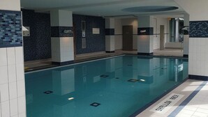Un'ampia piscina coperta con pareti e pavimento piastrellati.