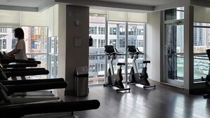 Una palestra con tapis roulant, ellittiche e un'ampia finestra vista città.