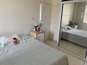 Cozy retreat with a single bed, nightstand, and mirror, perfect for a relaxing stay.