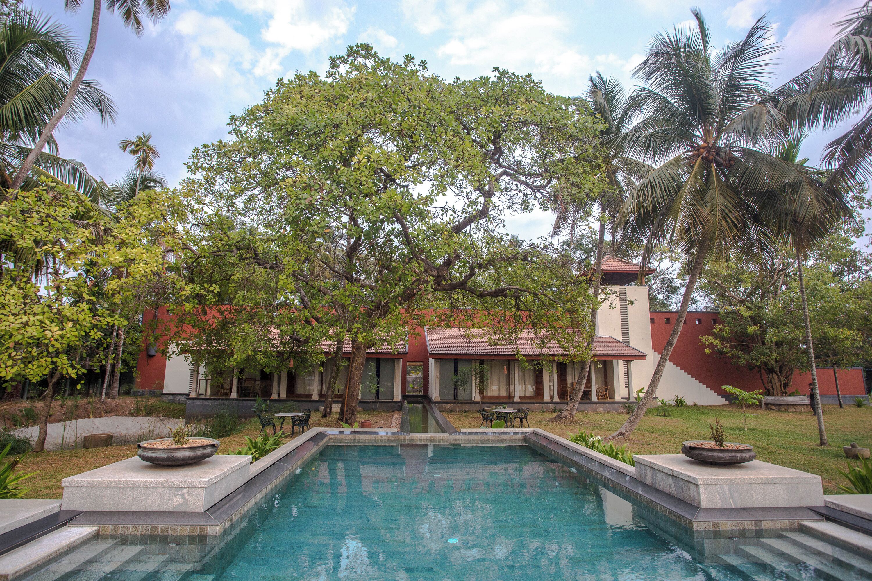 A pool area with a clear view of the surrounding landscape, including palm trees and a building with a red roof.