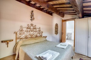Une chambre à coucher comprenant un lit, une table de chevet, une armoire et une porte donnant sur une salle de bain.