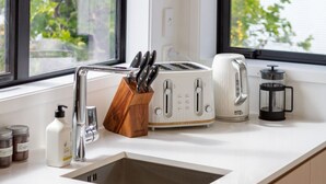 Una cocina con encimera blanca, cafetera, tostadora y bloque de cuchillos.