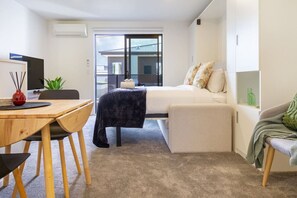Relax in a serene space with a comfortable bed, workspace, and outdoor balcony access.