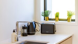 A modern kitchen with a sink, a kettle, a toaster, and a bottle of hand soap. - Metro Escape Studio across South City Mall (Christchurch)