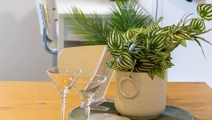 Ein modernes Wohnzimmer mit einem Holztisch, einem Blumentopf und einem an der Wand befestigten Flachbildfernseher.
