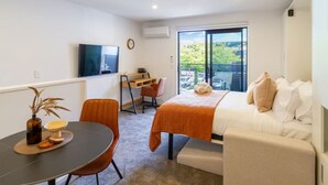 Ett modernt hotellrum med en säng, ett skrivbord och en TV.