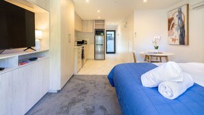Una habitación de hotel con cama, televisión, kitchenette y baño.