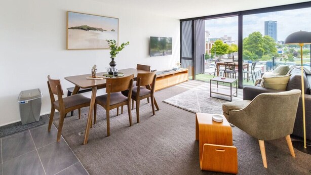 Ein modernes Wohnzimmer mit Essbereich, großen Fenstern und Blick auf die Stadt.