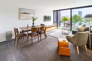 Una sala de estar moderna con comedor, ventanas amplias y vista a la ciudad.