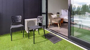 Un balcón con dos sillas, una mesita y un sofá dentro de una habitación.
