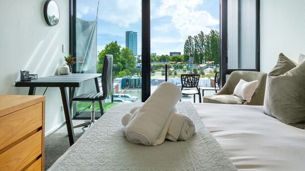 Una habitación de hotel con una cama, un escritorio, una silla y vistas a la ciudad.