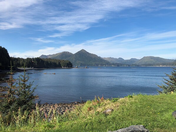 Ein stiller See mit Bergen im Hintergrund und einer grasbewachsenen Uferlinie.
