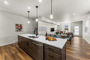 Una cocina moderna con una isla grande, electrodomésticos de acero inoxidable e iluminación colgante.