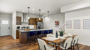 Una cocina moderna con una isla central, taburetes de bar y una mesa de comedor preparada para seis comensales.