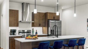 Una cocina moderna con electrodomésticos de acero inoxidable, armarios de madera y taburetes de bar azules.