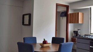 A dining area with a table, chairs, a bowl with an apple, a mirror, and a door leading to a kitchen. - depa 205 · Department in the Historic Center 205 (San Luis Potosí)