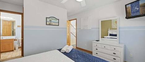 A bedroom with a bed, a dresser, a ceiling fan, and a framed picture on the wall.