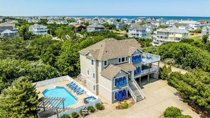 Une maison à deux étages avec une piscine, un patio couvert et une vue sur l’océan.