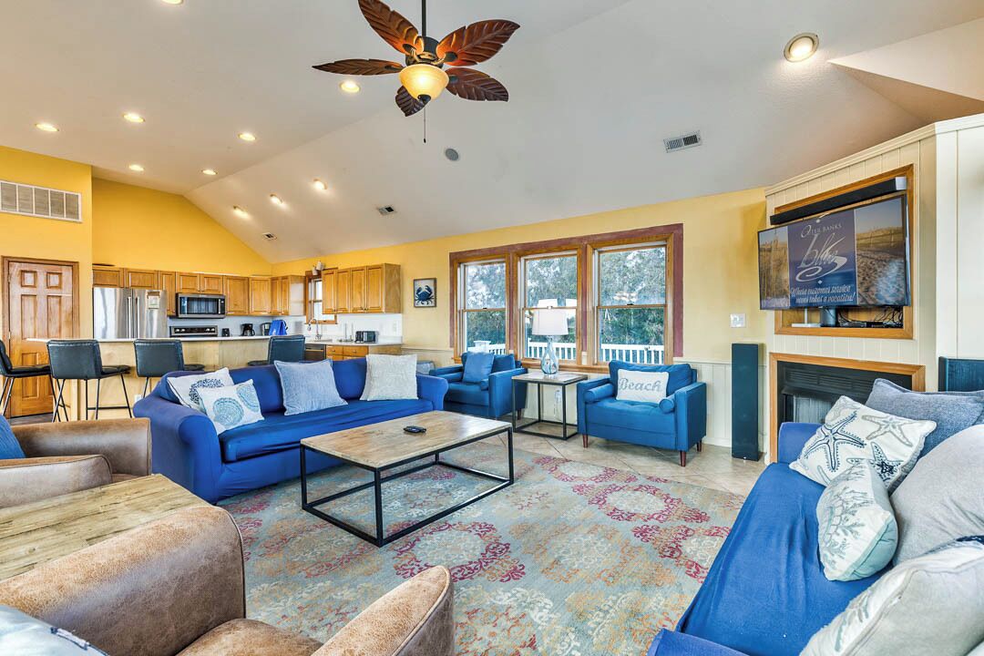 A spacious living room with blue sofas, a coffee table, and a ceiling fan.