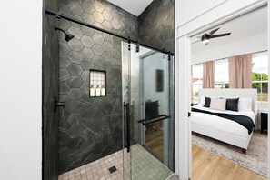 A modern bathroom with a glass shower enclosure, a black towel rack, and a hexagonal tile backsplash. - Luxury 3-bedroom Farmhouse with Pool Centrally Located in San Antonio (San Antonio)