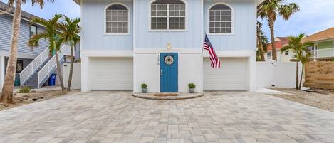 A two-story house with a blue door, an American flag, and a wreath on the front door.