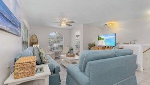 Un salon moderne avec un canapé, un téléviseur et un ventilateur de plafond.