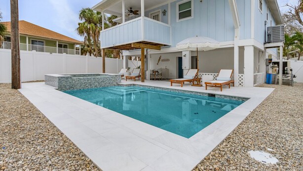 Une maison à deux étages dotée d’une piscine, d’un espace extérieur aménagé et d’un patio couvert.